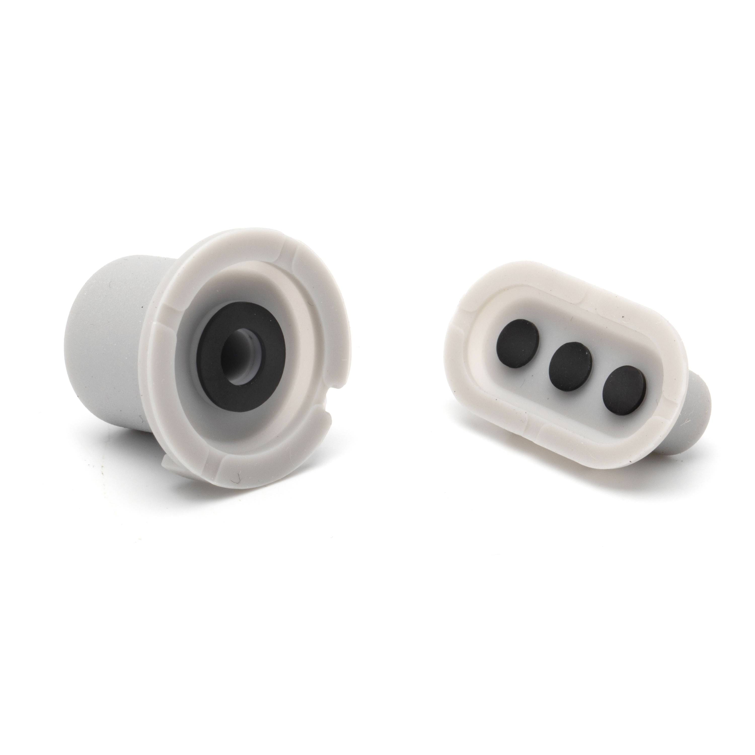 Two silicone earplug-like plugs shown on white background, one with a single central opening and one with three black openings.