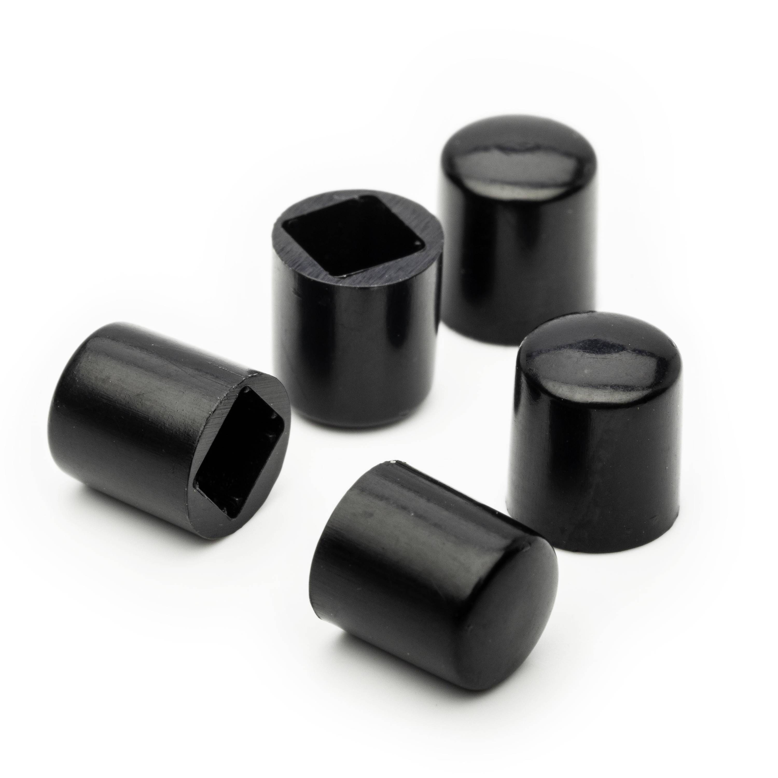Five black cylindrical caps or plugs on a white background, one showing a square opening and others closed ends.