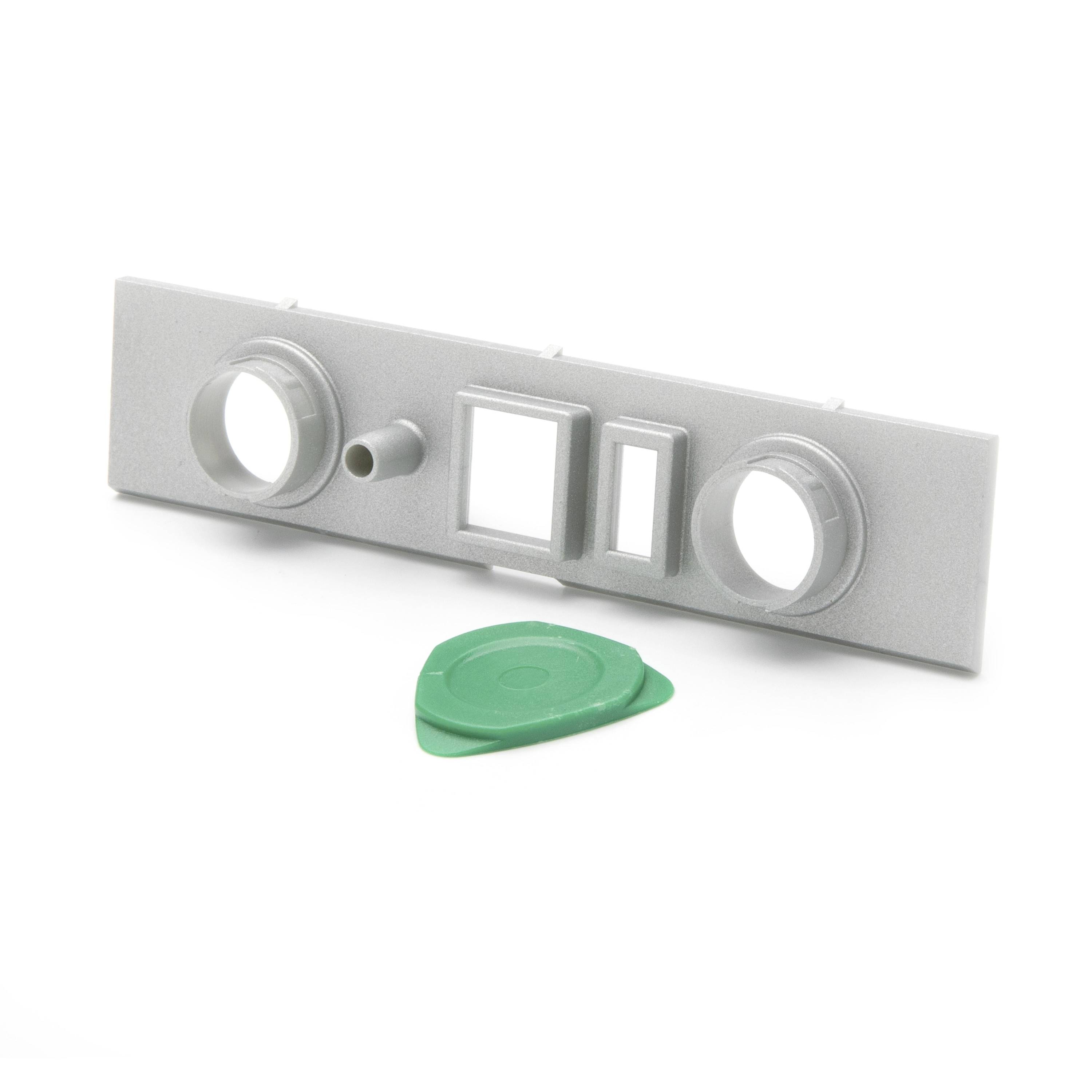 Gray plastic model front panel with two round openings, small nozzle, and two square windows, shown with a green detachable piece below.