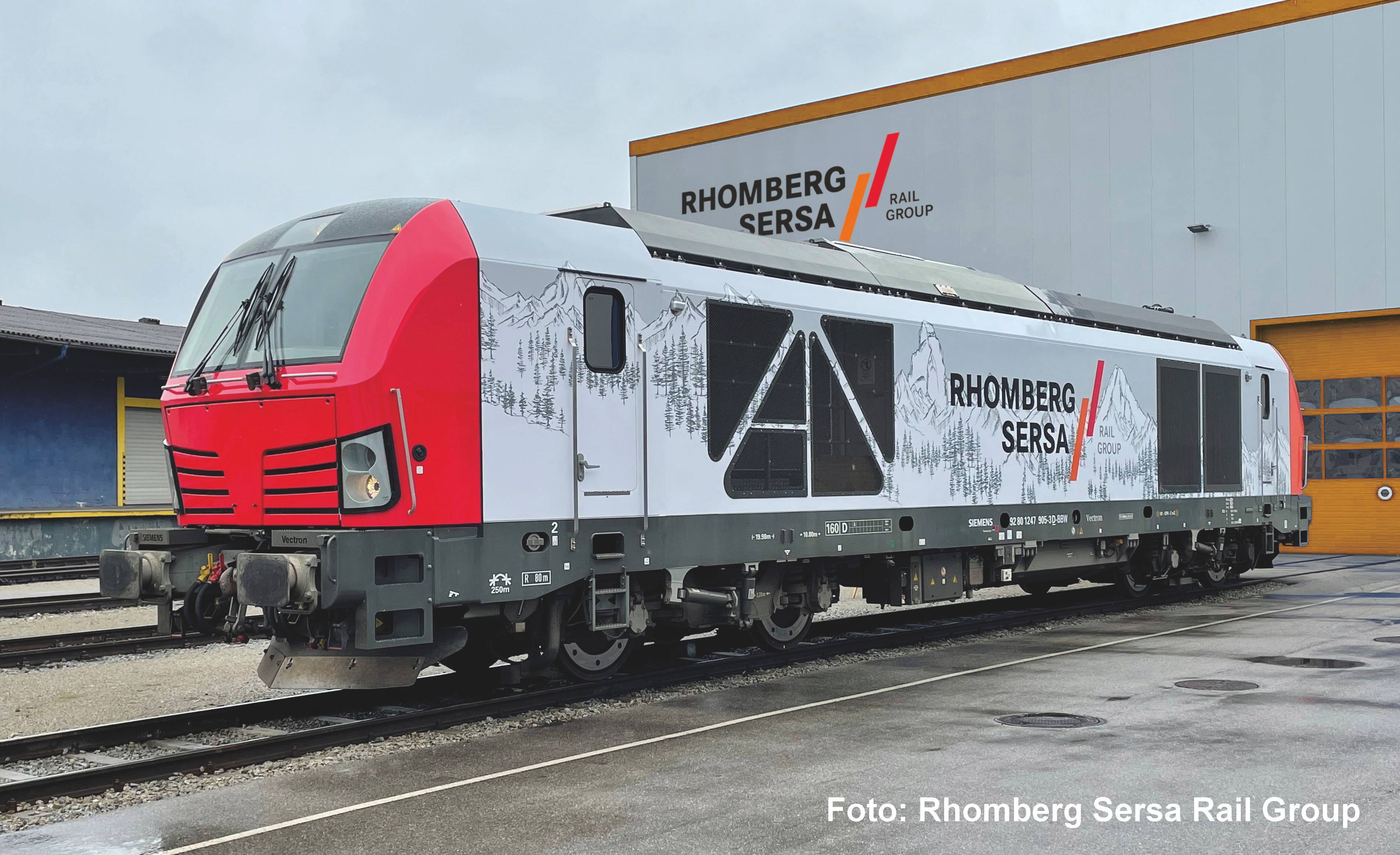 Un véhicule ferroviaire du Groupe Rhomberg Sersa Rail parké à l'extérieur devant un bâtiment de l'entreprise, présenté en vue latérale avec une livrée rouge et blanche.
