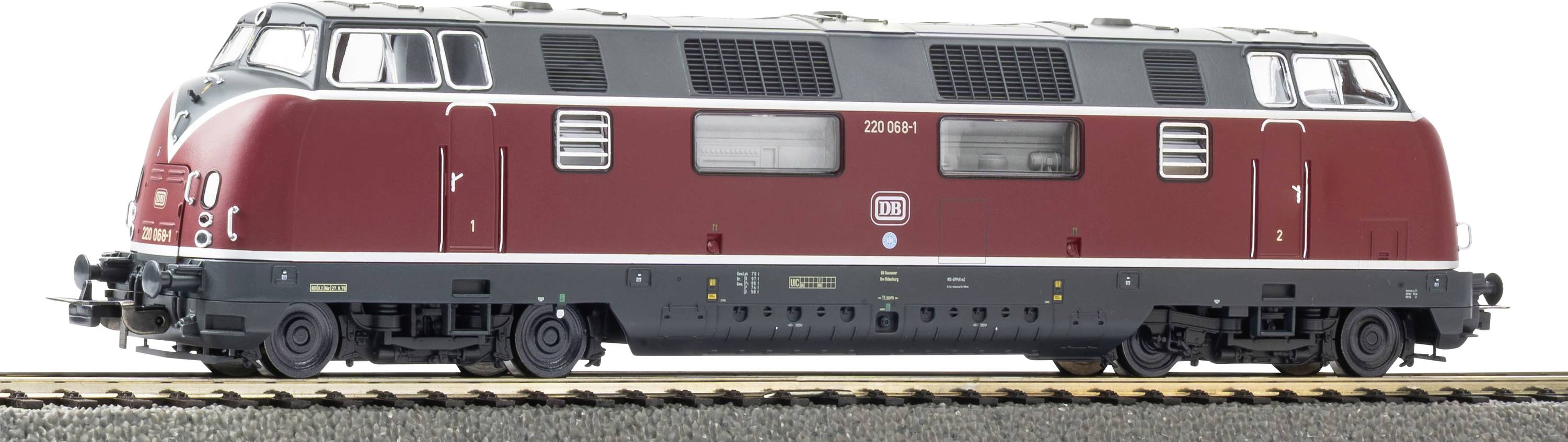Vue latérale d'une locomotive diesel rouge et grise sur des rails de chemin de fer, présentée sur un fond blanc.