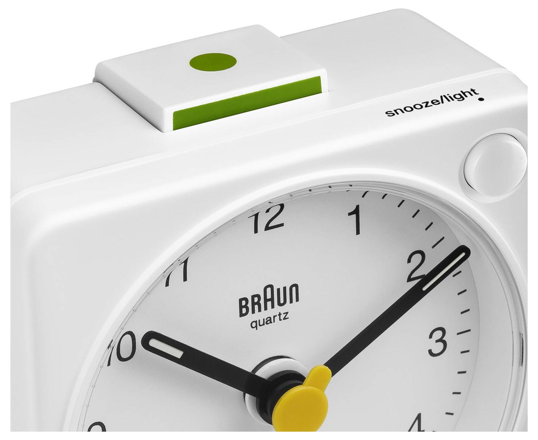 Gros plan d'un réveil à quartz blanc Braun avec bouton « snooze/lumière » et aiguilles jaunes, affichant environ 2h50.