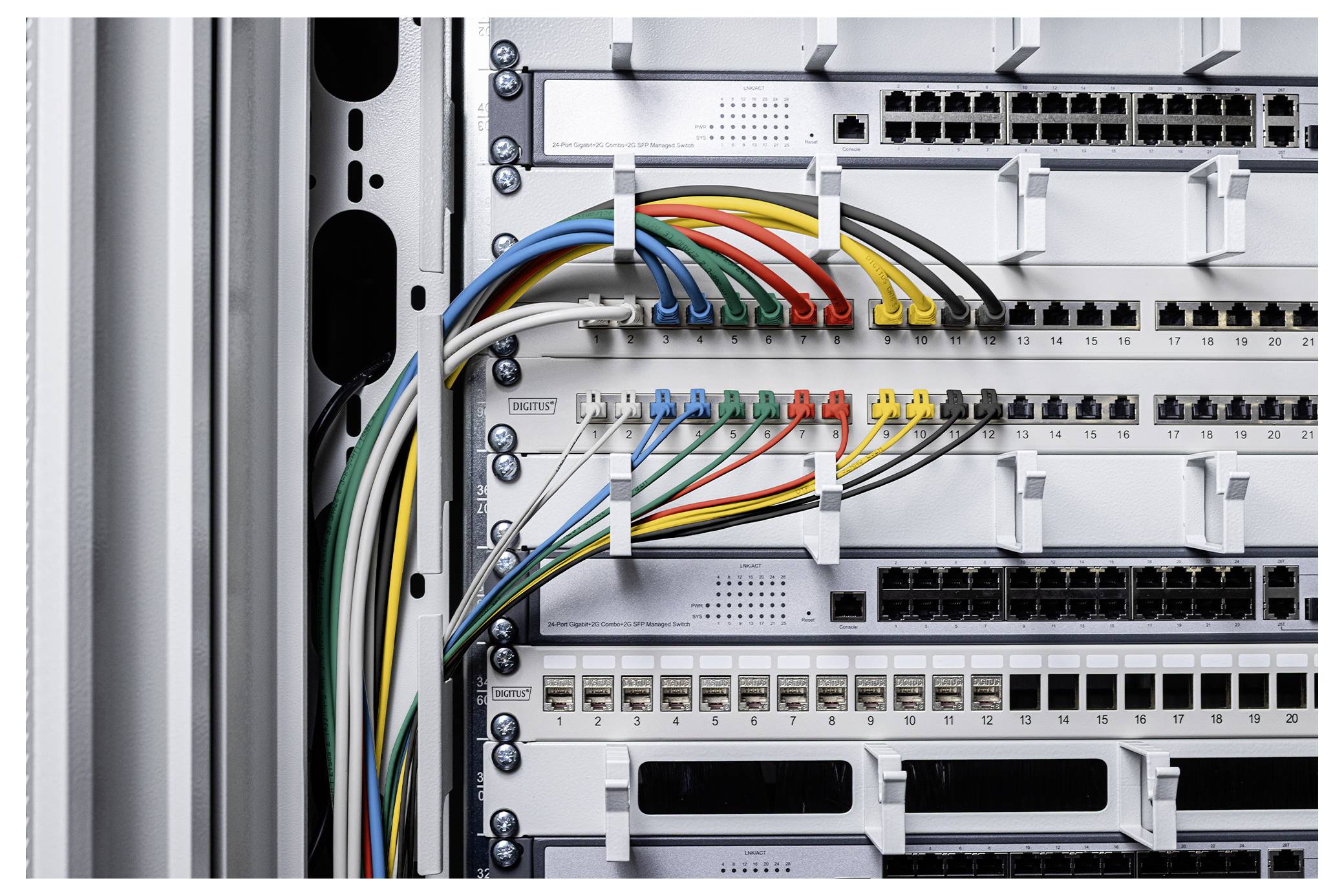 Gros plan d'une baie de serveurs réseau avec plusieurs commutateurs Ethernet et des câbles codés par couleur connectés à des ports numérotés.