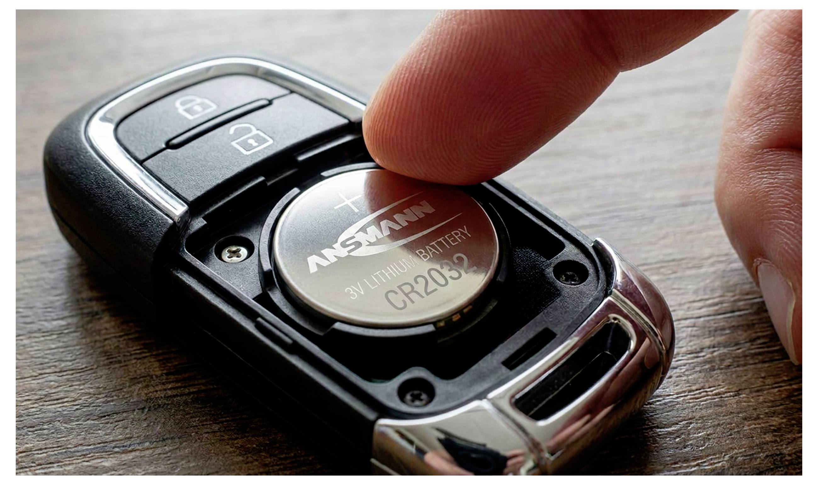 Gros plan d'une télécommande de voiture avec un doigt appuyant sur la batterie CR2032 à l'intérieur, montrant le compartiment de la batterie et les boutons de verrouillage/déverrouillage.