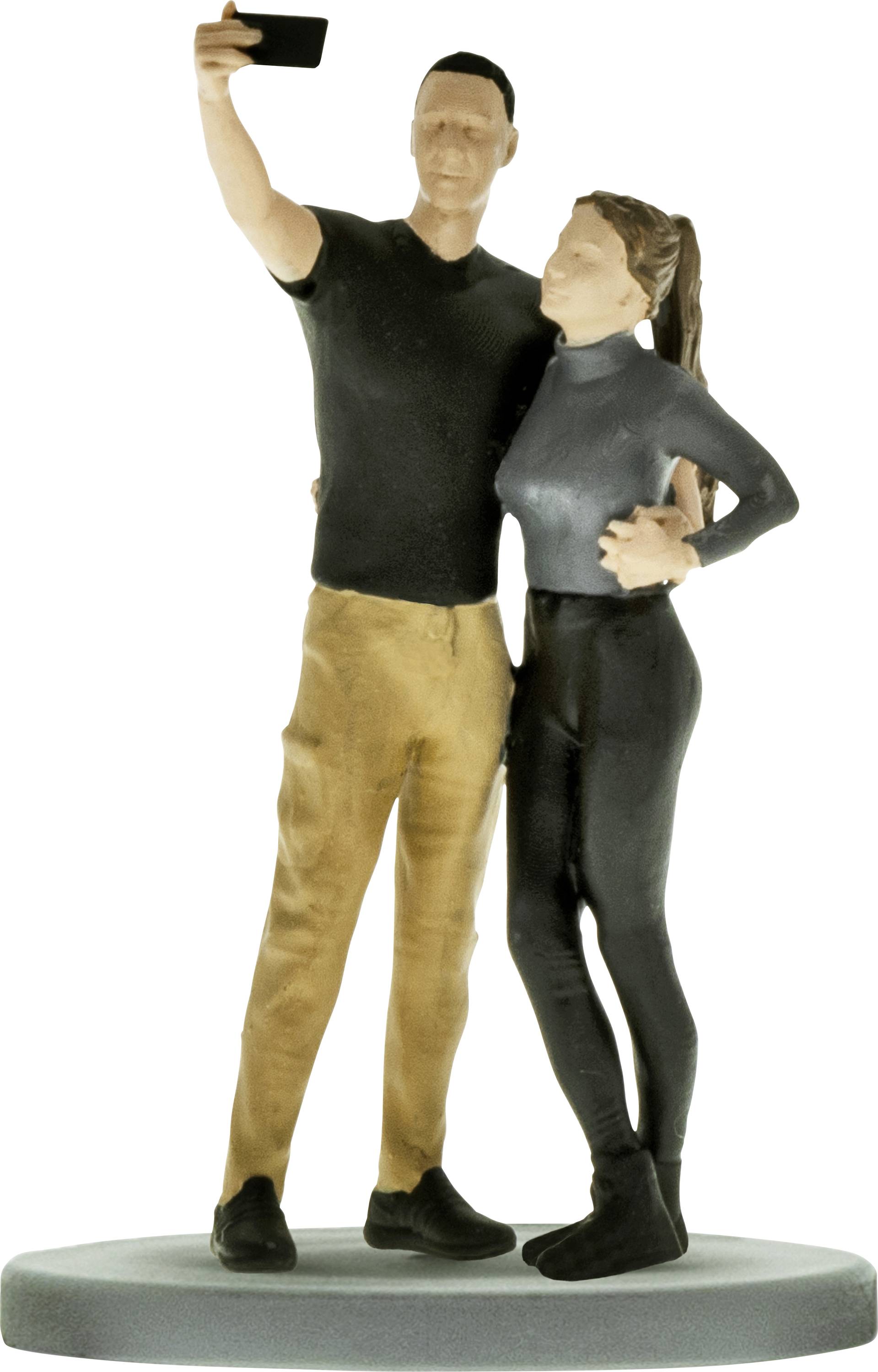 Un figurine d'homme et de femme posant pour un selfie, debout ensemble sur une base ronde.