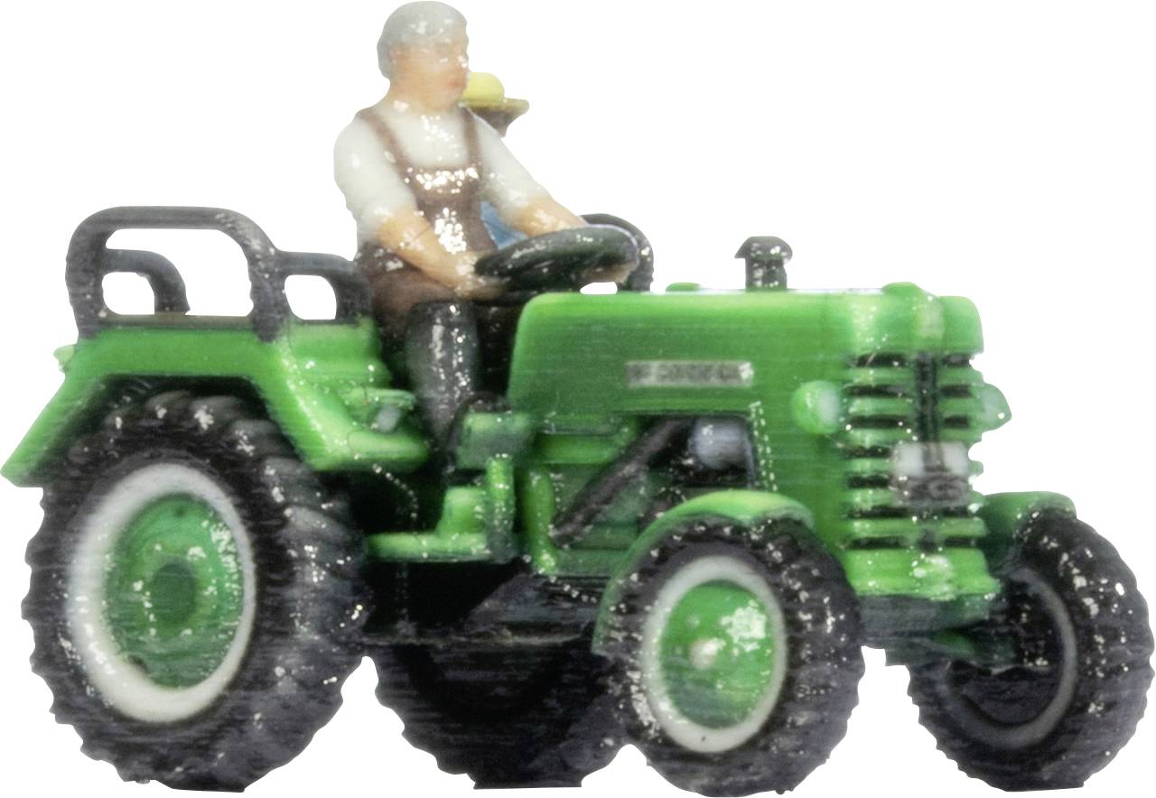 Tracteur jouet vert avec une figurine de conducteur assis, présenté en vue de profil sur un fond neutre.