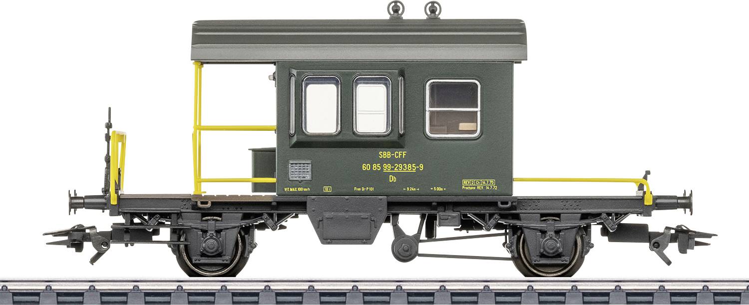 Vue latérale d'un modèle réduit de wagon de chemin de fer vert foncé sur les rails, avec des rampes jaunes, de petites fenêtres et des marquages ferroviaires imprimés.