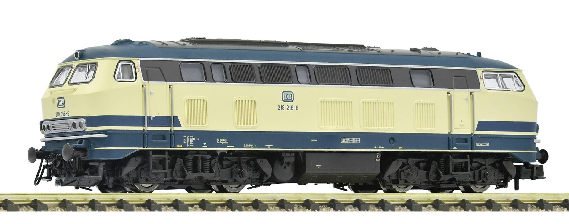Vue latérale d'une locomotive diesel bleu et crème isolée sur fond blanc, montrant la longueur du moteur et les détails du toit.