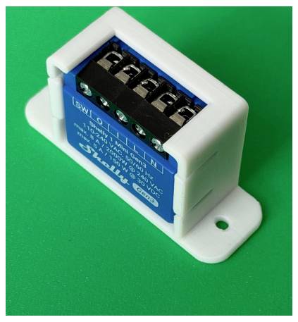Petit module électronique bleu dans un support en plastique blanc avec bornes à vis, montré sur un fond vert.