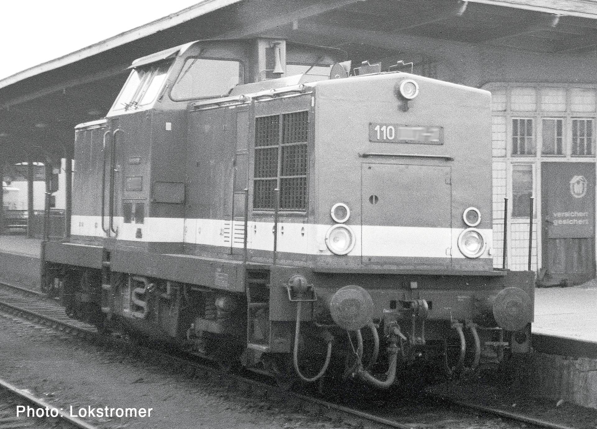 Une locomotive diesel numérotée 110 se tient sur un quai de gare en noir et blanc, vue de l'avant-gauche.