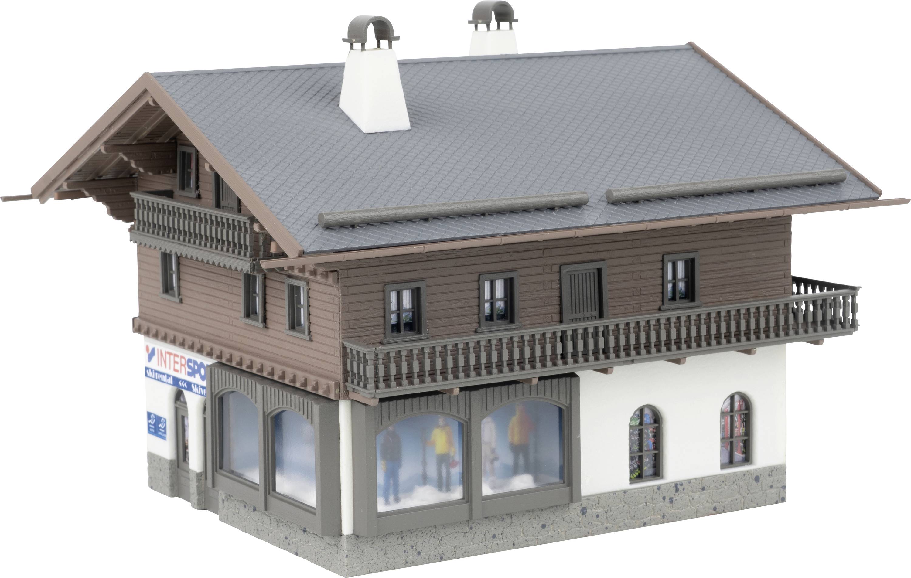 Maquette d'un bâtiment de style alpin à deux étages avec un toit gris, des balcons, des vitrines commerciales et un niveau inférieur blanc sur un fond neutre.