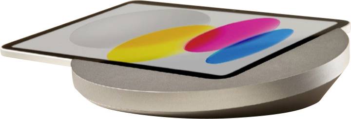 Une tablette repose sur un support de recharge sans fil argenté, avec un écran affichant trois formes ovales colorées qui se chevauchent.