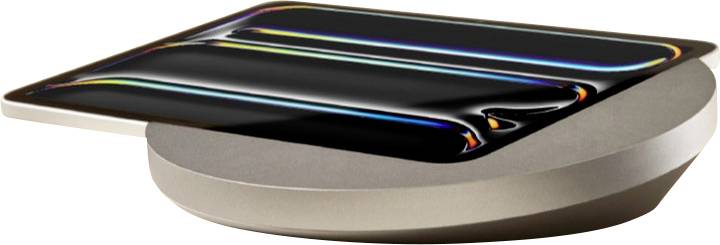 Un smartphone noir brillant repose face vers le haut sur un socle de chargement sans fil de forme ovale beige.