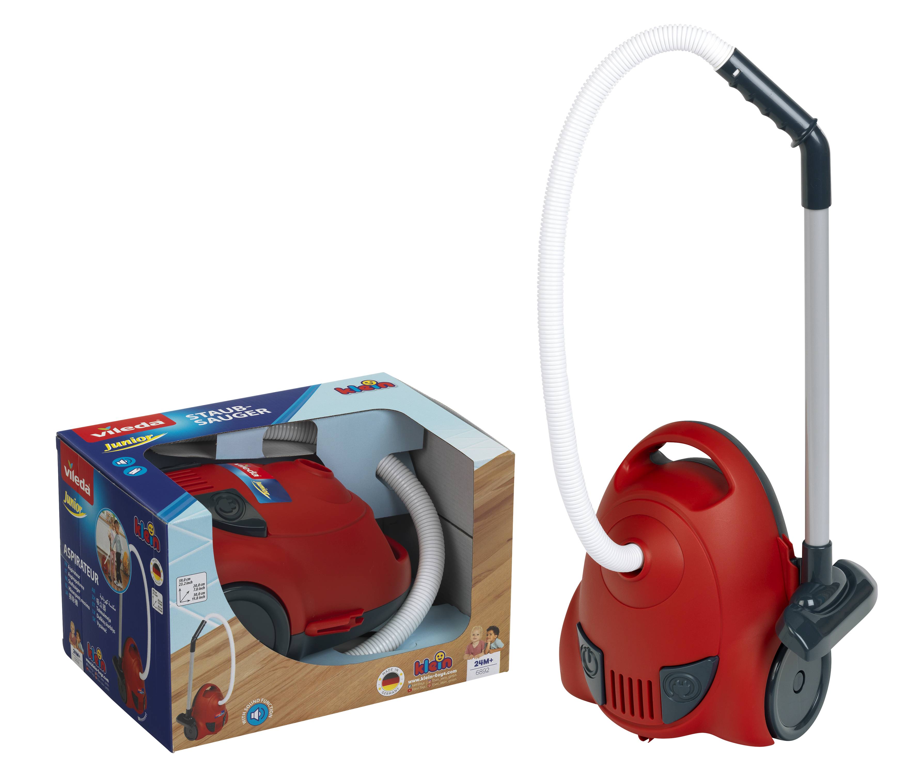 Aspirateur jouet rouge avec tuyau et poignée à côté de sa boîte d'emballage, présenté sur un fond blanc.