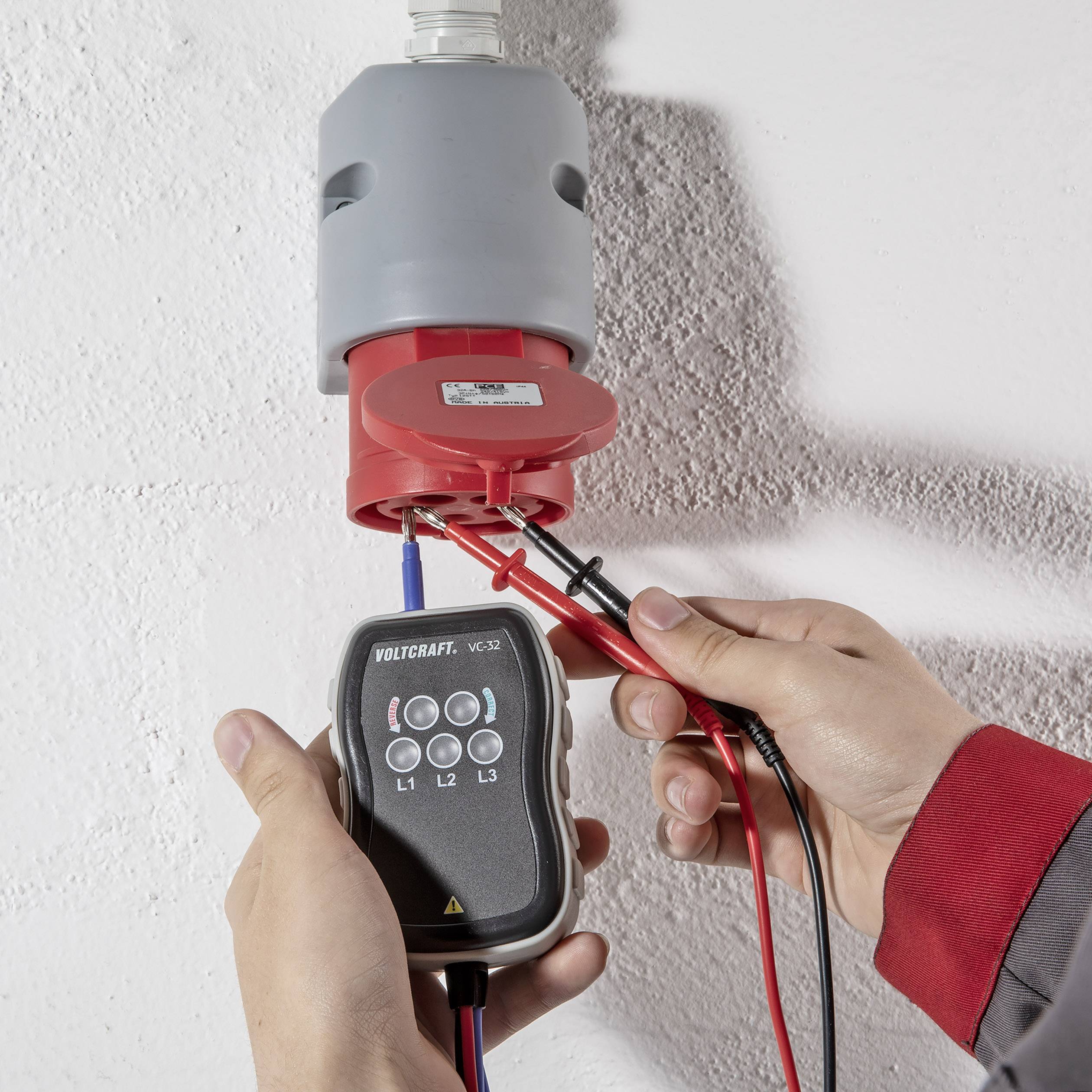 Un technicien utilise un multimètre pour effectuer des mesures électriques sur un connecteur à trois fils.