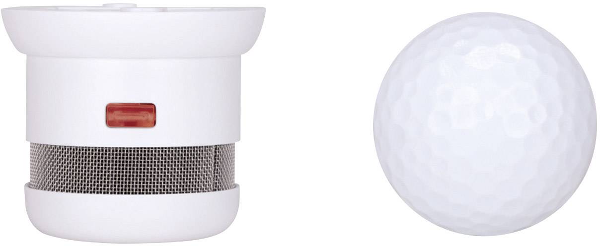 'Petit détecteur de fumée rond à côté d'une balle de golf pour comparer les tailles. Détecteur de fumée avec bouton rouge et grille, diamètre similaire à celui d'une balle de golf.'
