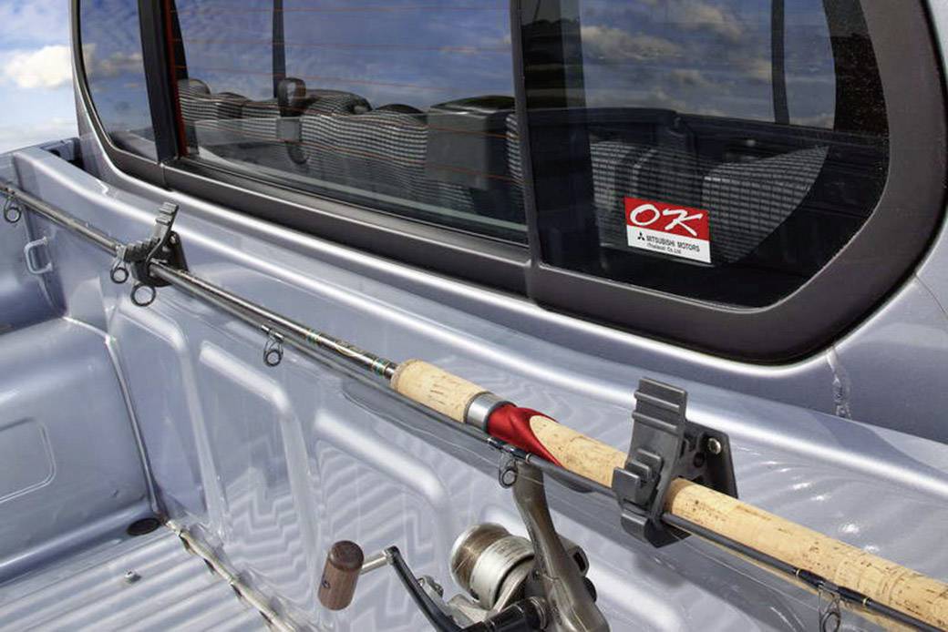 Canne à pêche montée dans un support sur la surface de chargement d'un pick-up argenté.