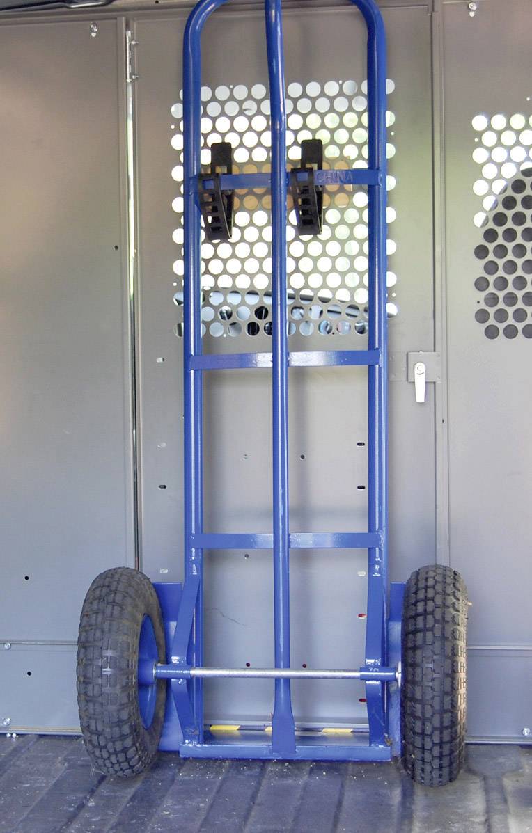 'Chariot à deux roues bleu adossé à un mur ; poignée et roues bien visibles. Utilisé pour le transport d'objets lourds.'