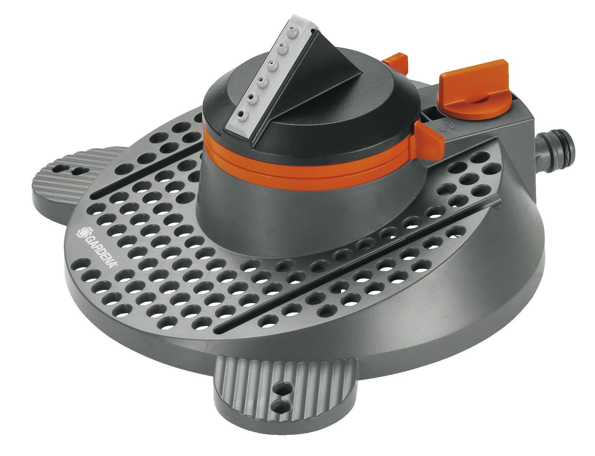 Arroseur de jardin gris avec des touches orangées, à tête rotative ronde, installé sur un socle plat percé de trous pour une distribution uniforme de l'eau.