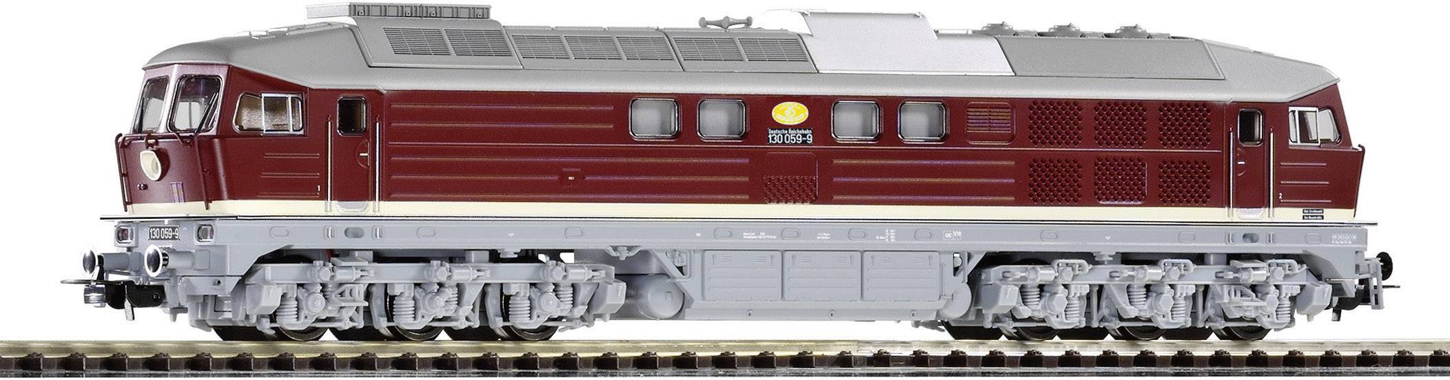 Un train miniature en rouge foncé et gris sur un rail. Il possède plusieurs roues et des détails sur sa partie supérieure.