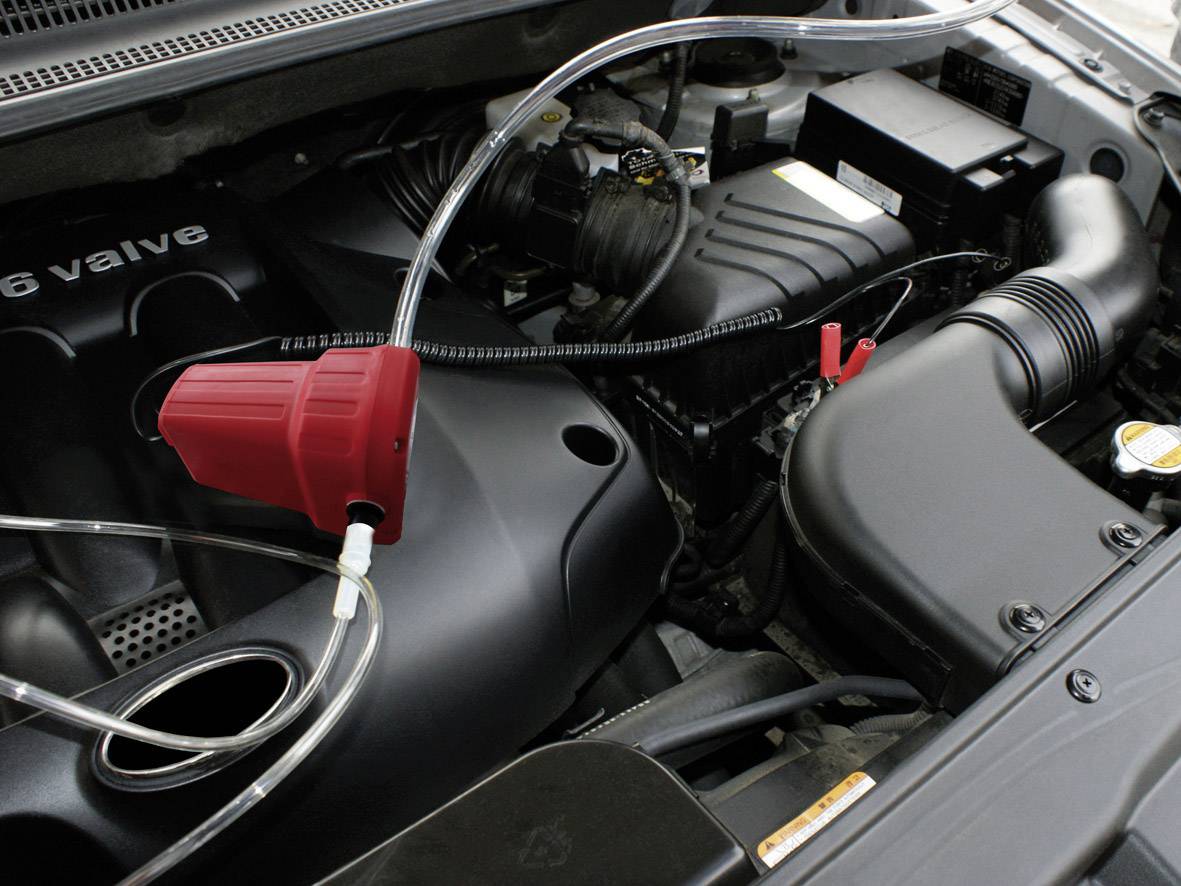 Un moteur automobile avec un entonnoir rouge et un tuyau transparent utilisé pour le remplissage de liquide.