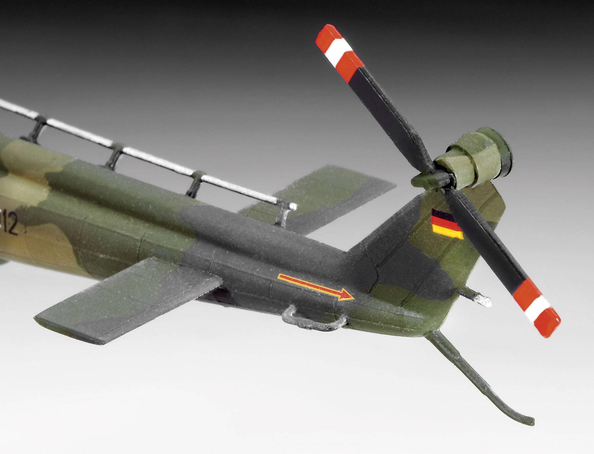 Modèle d'un hélicoptère militaire avec peinture de camouflage et emblème du drapeau allemand. Rotor de queue pivotant avec des bandes rouges distinctives.