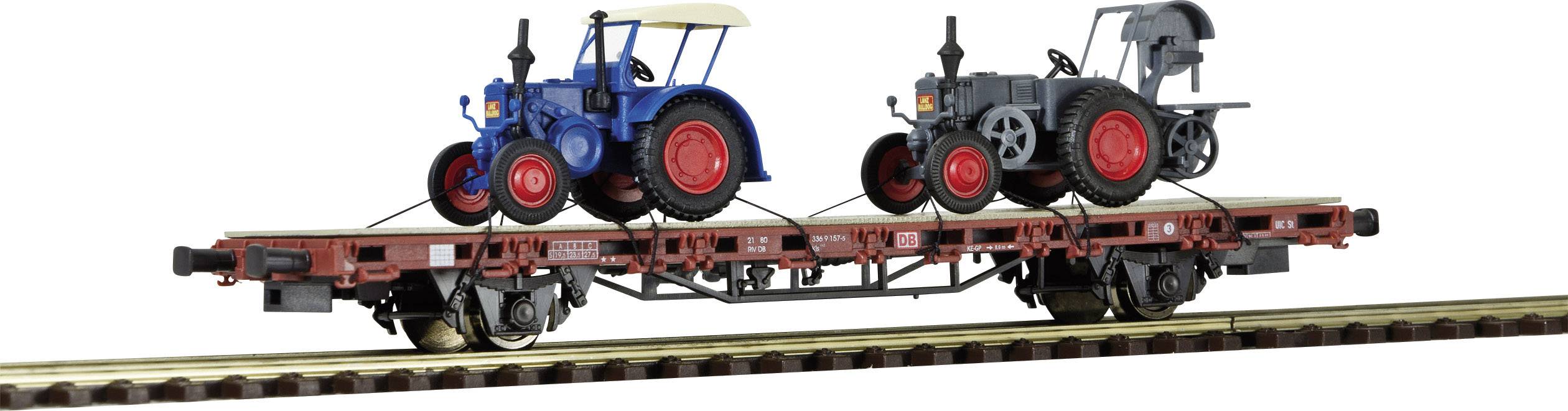 Deux petits modèles de tracteurs, l'un bleu et l'autre gris, sont placés sur un wagon de marchandises miniature le long d'un rail de chemin de fer miniature.
