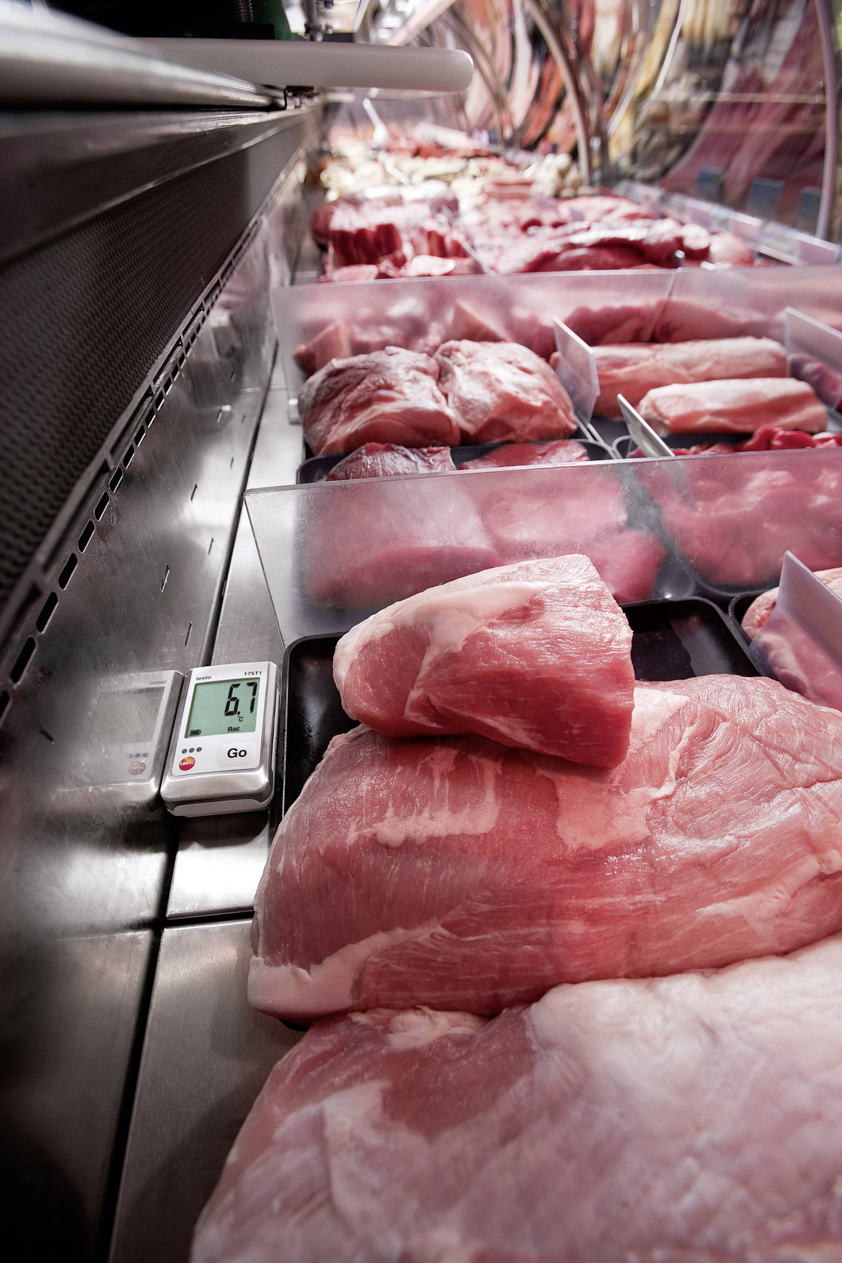De la viande fraîche est disposée dans une vitrine de boucher. Un thermomètre indique 6,9 degrés Celsius, montrant ainsi la température de conservation.