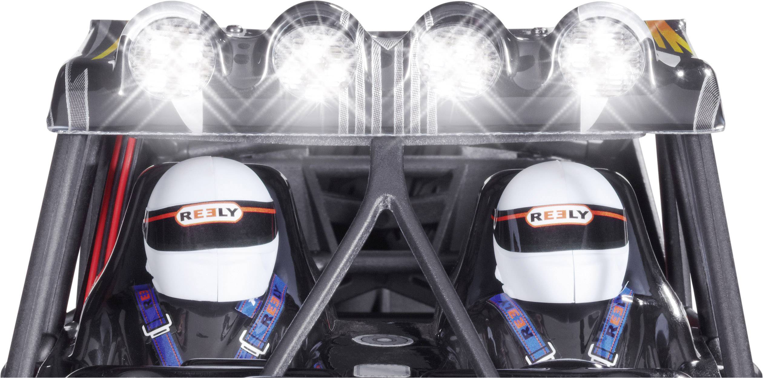 Deux pilotes de course portant des casques blancs sont assis côte à côte dans un véhicule. Au-dessus d'eux, une rangée de projecteurs lumineux brille.