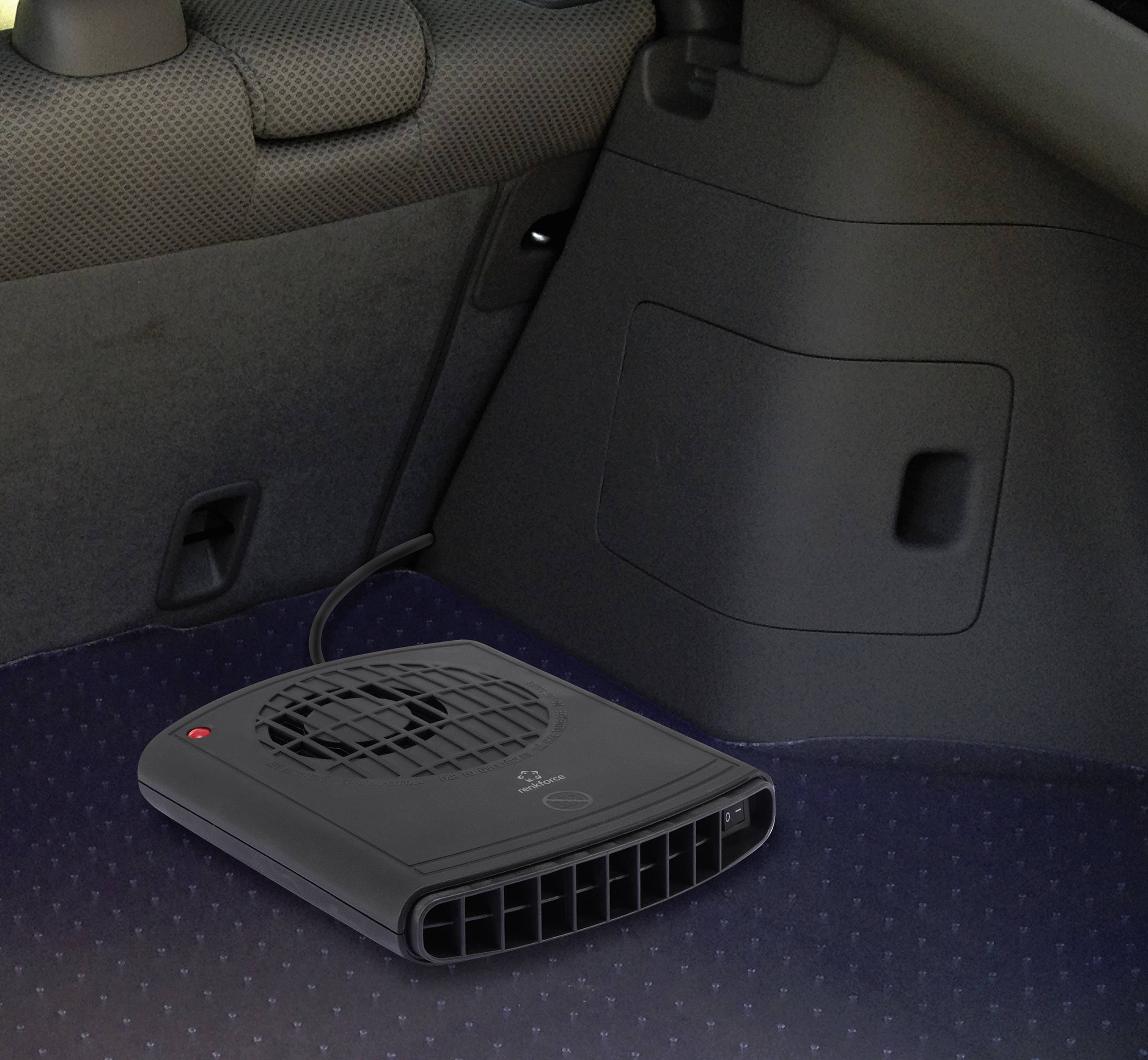 Un petit chauffage électrique noir avec ventilateur est posé sur le sol d'une voiture, près d'un siège. Il est positionné vers l'entrée d'air.