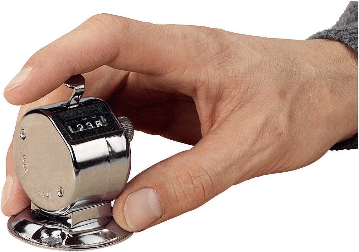 Une main tient un compteur mécanique affichant '236'. L'appareil en métal, tenu dans la paume, est typique des comptages manuels.