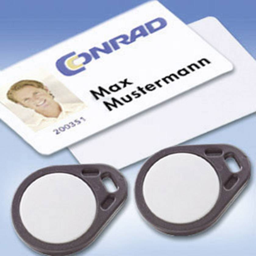 'Badge nominatif avec photo et nom 'Max Dupont' sur une carte d'entreprise, deux porte-clés avec cartes RFID.'
