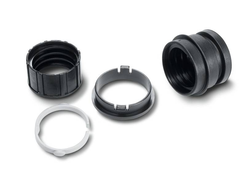 Quatre bagues en plastique noir et une bague en plastique blanc sur un fond blanc, servant de composant d'un connecteur ou d'un élément mécanique.