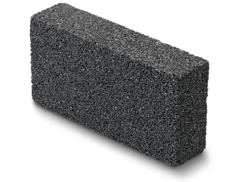 Une pierre à aiguiser rectangulaire, sombre, à la surface rugueuse et poreuse. Utilisée pour éliminer la rouille ou travailler les surfaces.