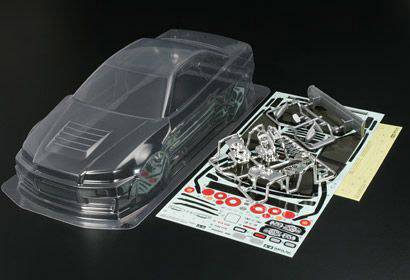 Une carrosserie transparente de voiture miniature à côté de plusieurs pièces en plastique et d'autocollants sur un fond noir, prête à être assemblée.
