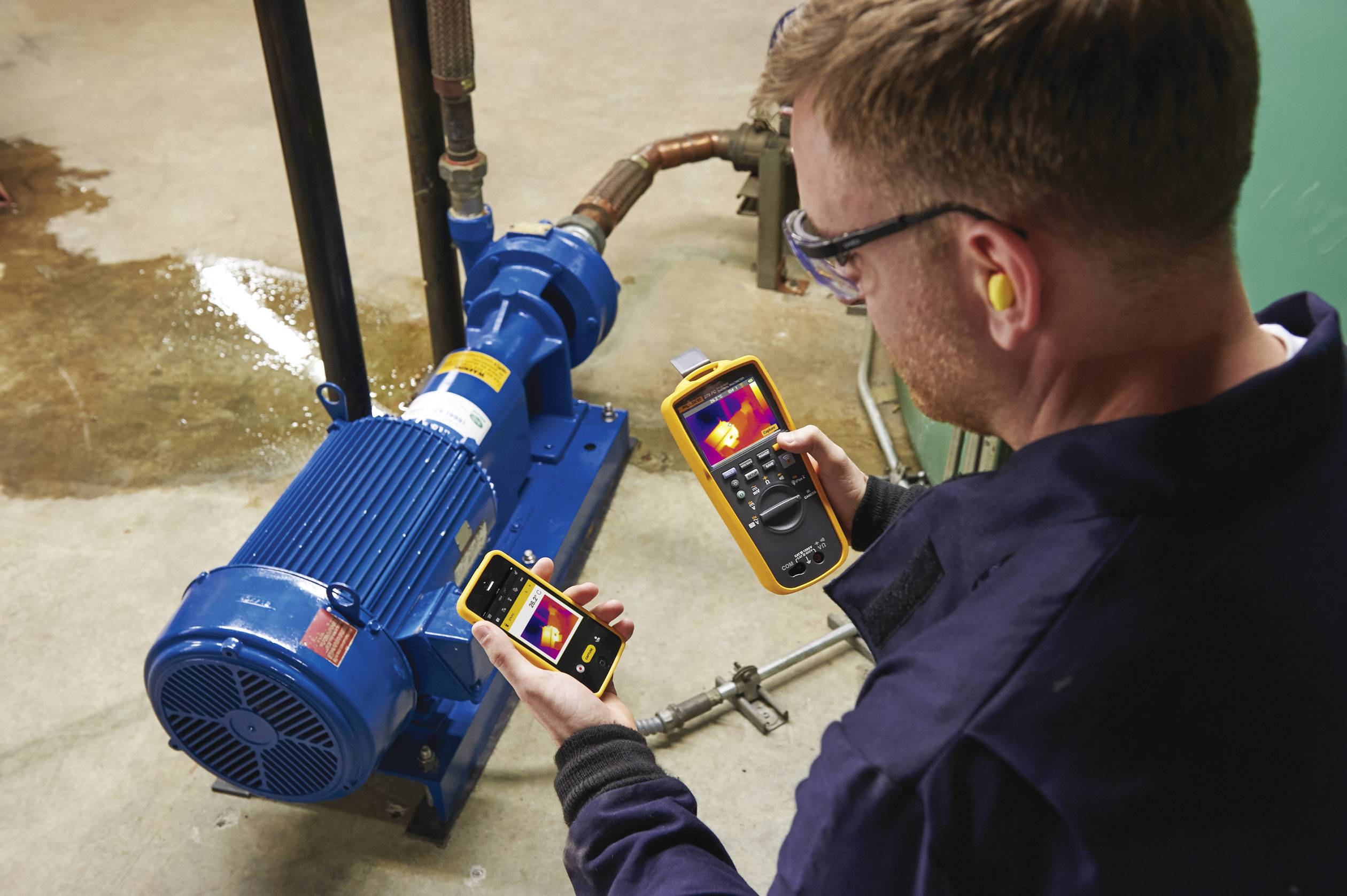 Un technicien utilise une caméra thermique et un instrument de mesure pour vérifier la température et le fonctionnement d'un moteur électrique.