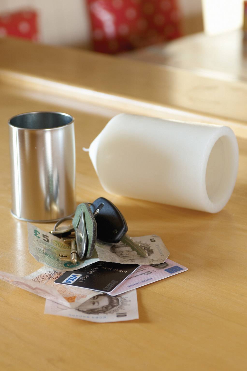 Sur une table sont posés un chandelier, une bougie blanche, des billets de banque et des clés.