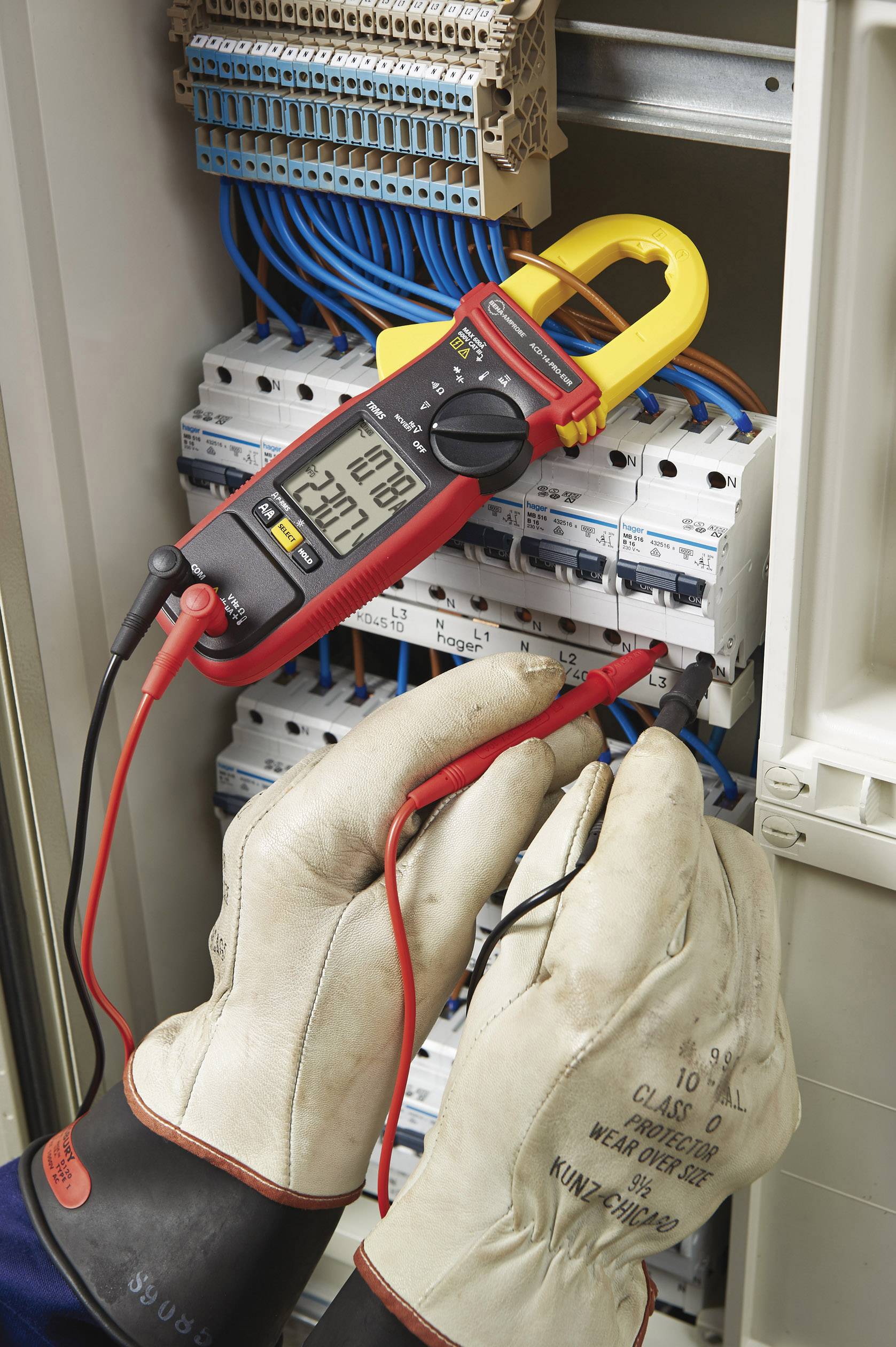 Une personne portant des gants de protection mesure le courant électrique dans un coffret électrique à l'aide d'un multimètre numérique.