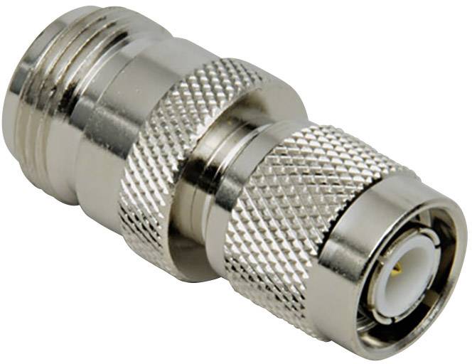 Un adaptateur métallique argenté, probablement une fiche coaxiale, avec des sections striées et lisses, est posé sur un fond blanc.