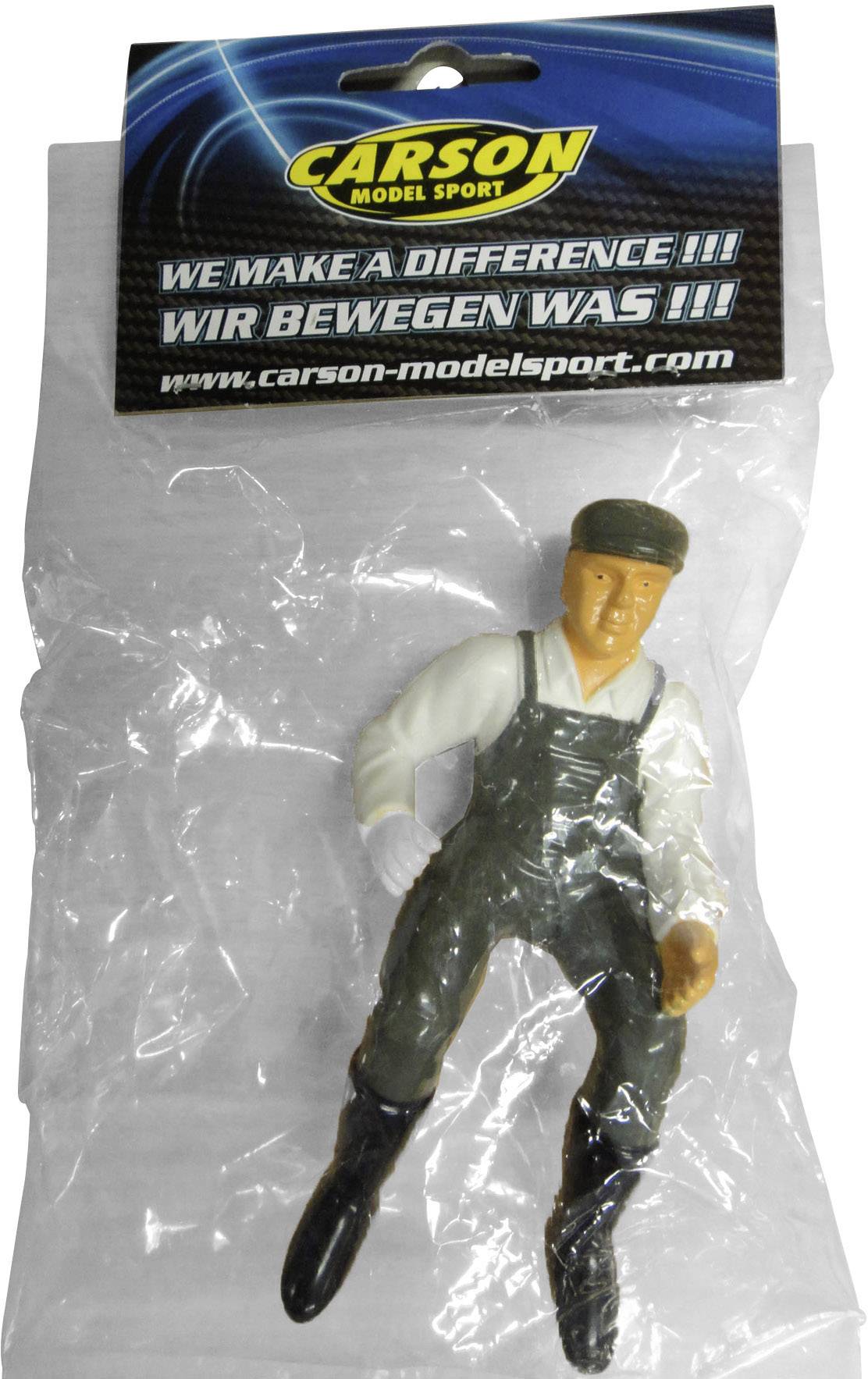 Une figurine en plastique portant des vêtements de travail dans un sachet de 'Carson Model Sport' avec le slogan 'WE MAKE A DIFFERENCE !!! NOUS FAISONS LA DIFFÉRENCE !!!'.