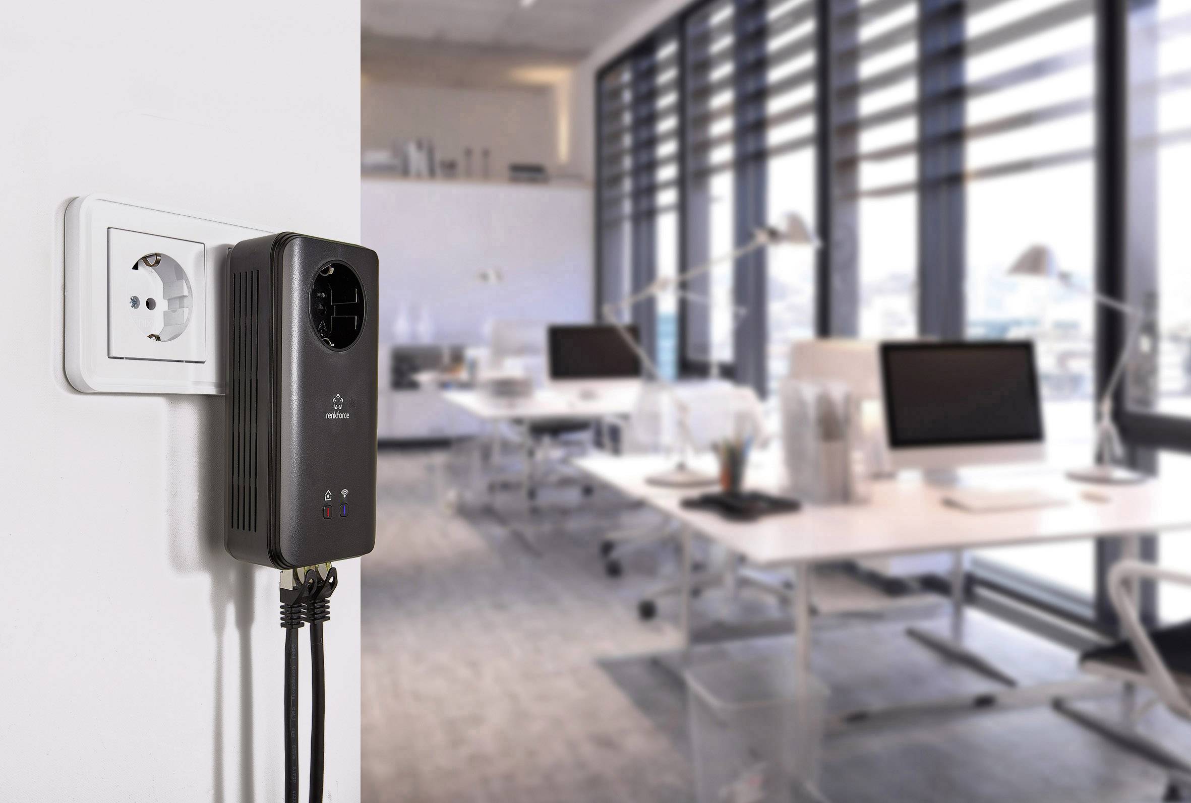 Un régulateur de tension est branché dans une prise électrique dans un bureau moderne. En arrière-plan, on aperçoit des bureaux et des ordinateurs.