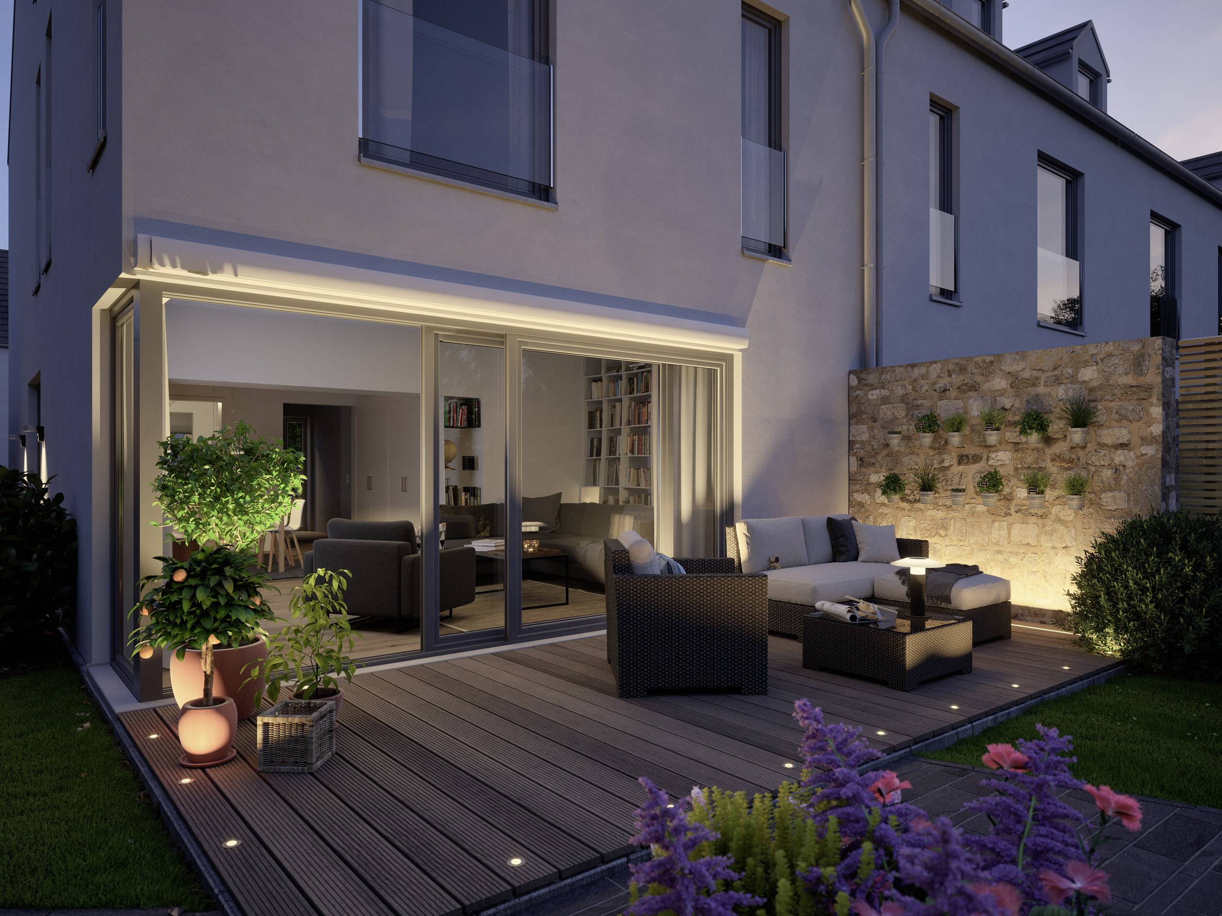 Une terrasse moderne au crépuscule avec des meubles de salon confortables, des plantes et un éclairage subtil devant un espace de vie bien éclairé.