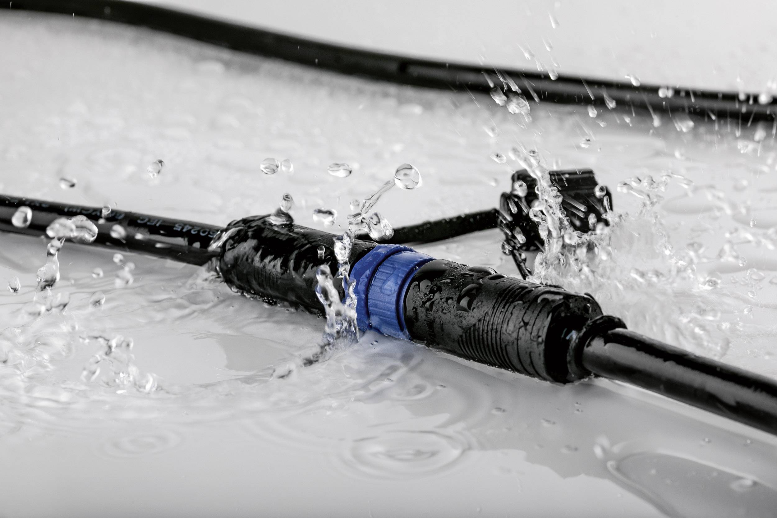 Connecteur de câble résistant à l'eau, placé sous des éclaboussures sur une surface lisse ; illustre le type de protection contre les liquides.
