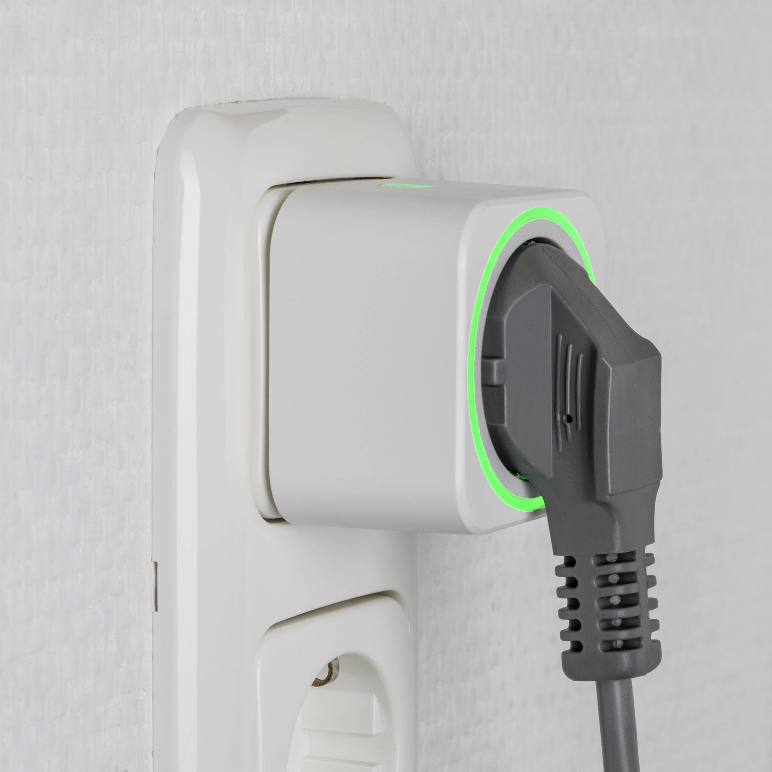 Une fiche noire est branchée dans une prise blanche, avec un anneau lumineux vert autour de la fiche, indiquant le processus de charge.