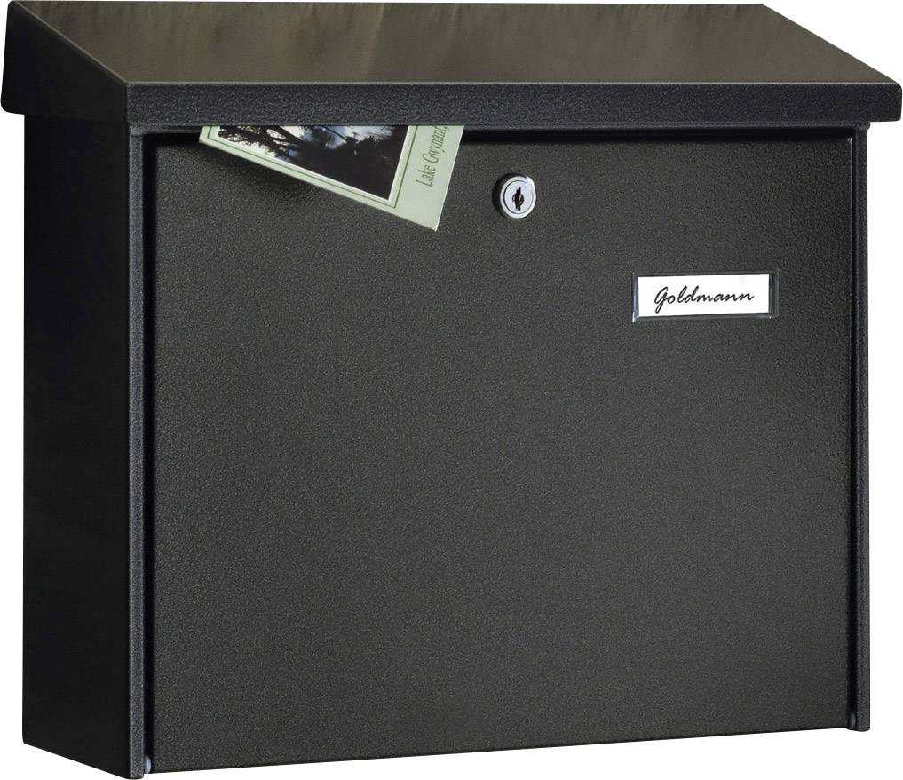Une boîte aux lettres noire avec un support pour cartes postales dépassant au-dessus. Sur la boîte aux lettres est inscrit le nom 'Goldmann'.