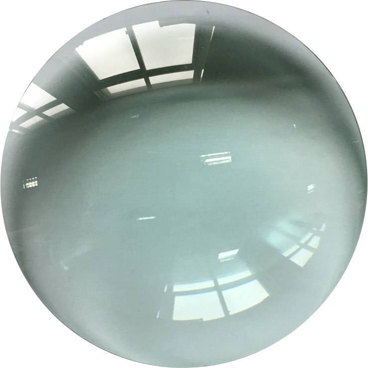 Table ronde en verre brillant sous un éclairage plafonnier lumineux. Les reflets des fenêtres sont visibles sur sa surface.
