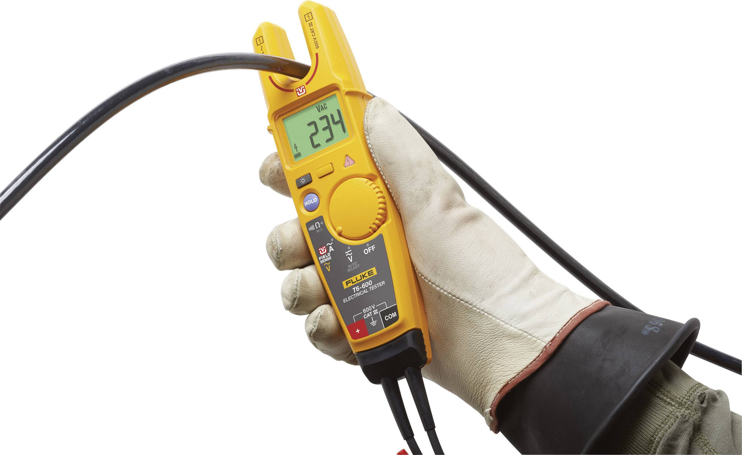Une main gantée d'un gant en caoutchouc tient un multimètre numérique orange affichant 234 volts.