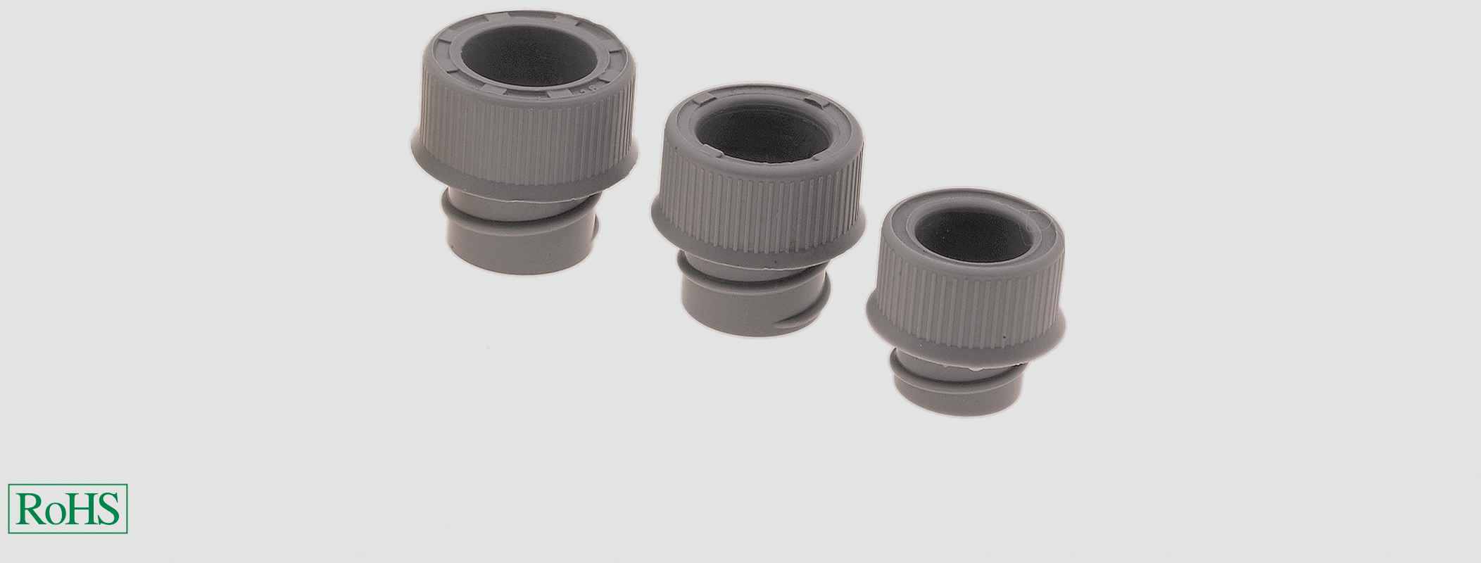 Trois presse-étoupes gris de différentes tailles sur un fond clair. Un symbole 'RoHS' est situé en bas à gauche.