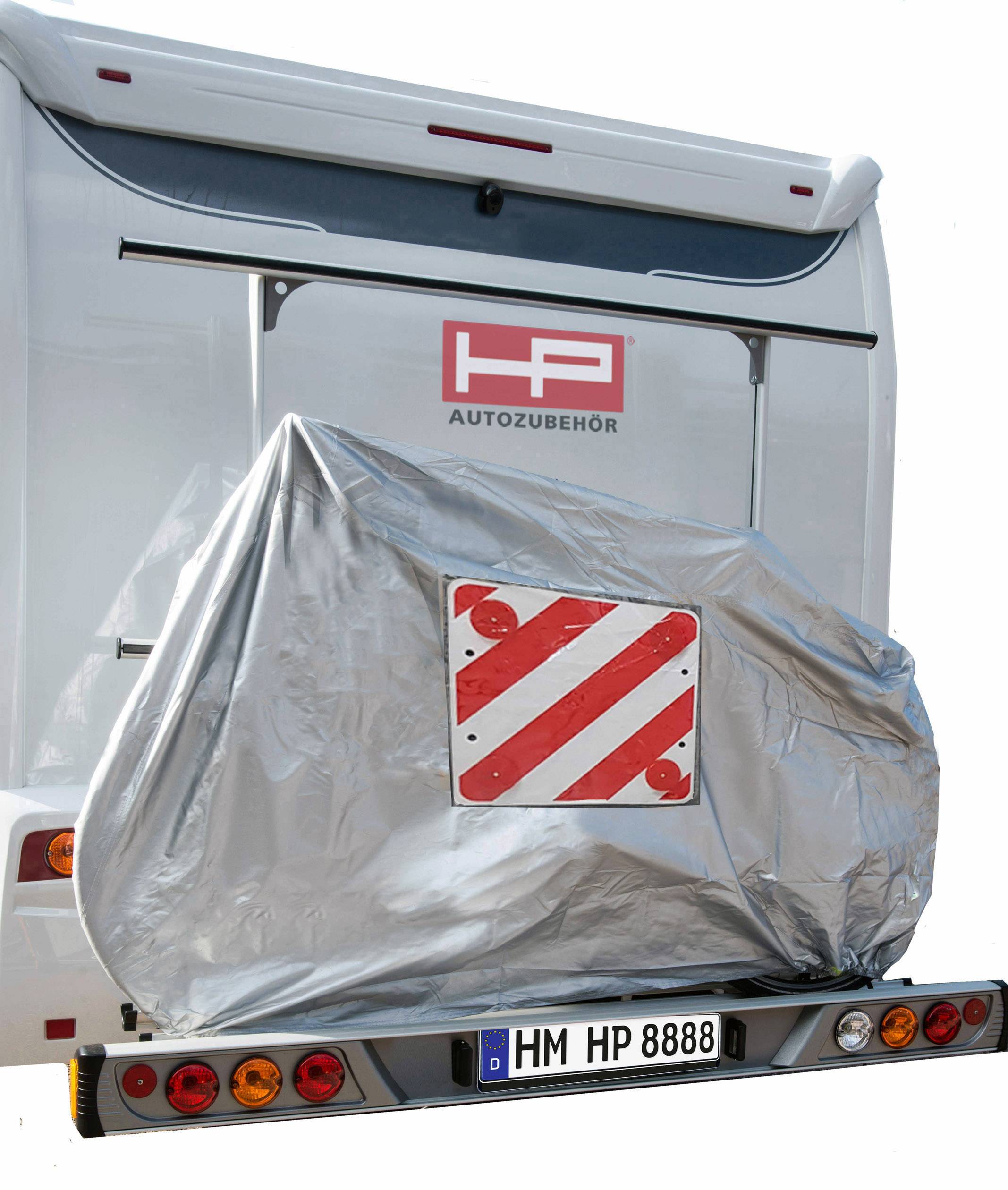 Un véhicule avec un porte-bagages arrière, recouvert d'une bâche. Un triangle de signalisation rouge et blanc est visible. Plaque d'immatriculation : 'HM HP 8888'.