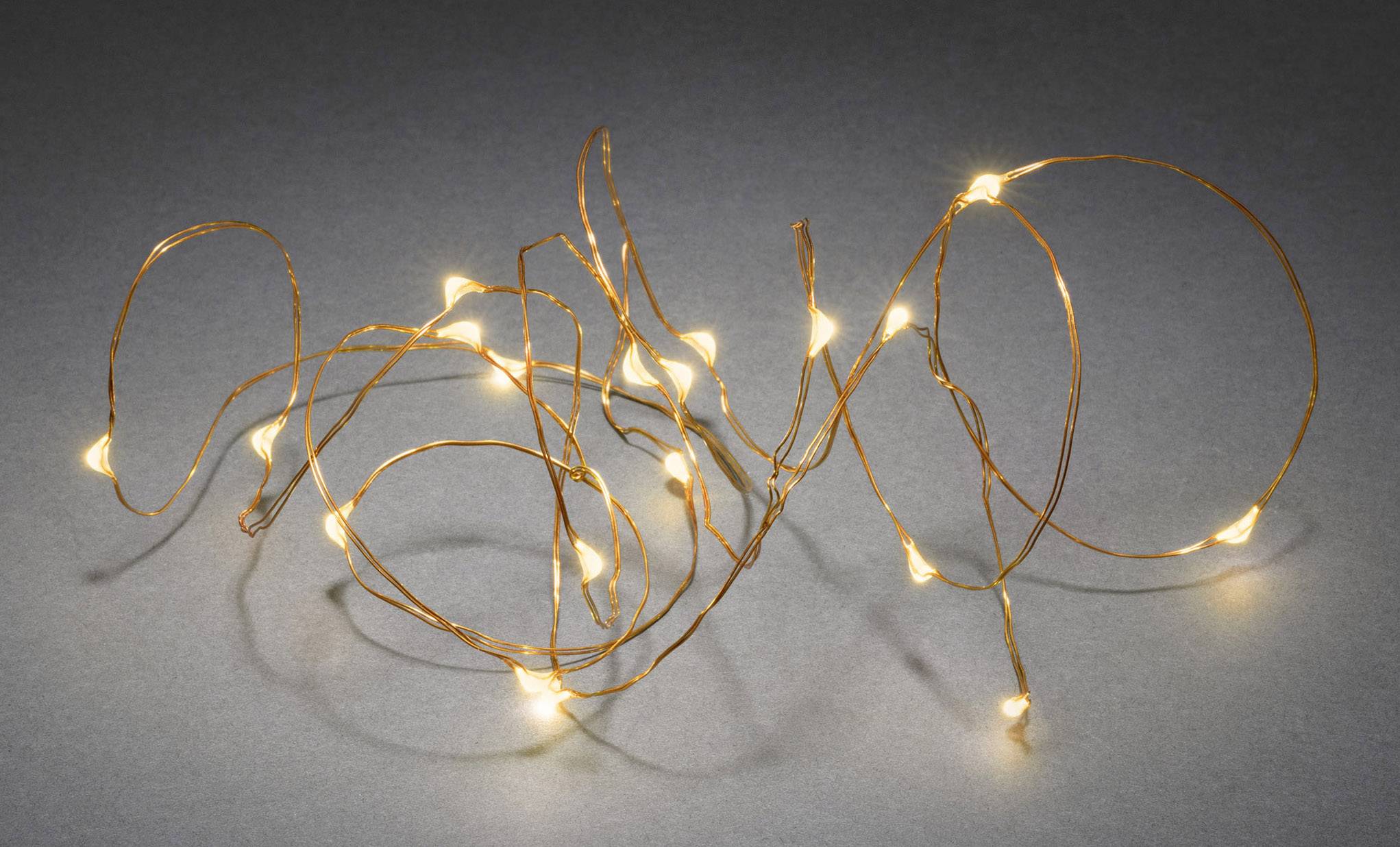 Une guirlande lumineuse à LED blanc chaud est disposée en motifs sinueux sur une surface grise.
